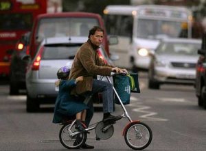 Viscount Linley with child on Strida in busy London street