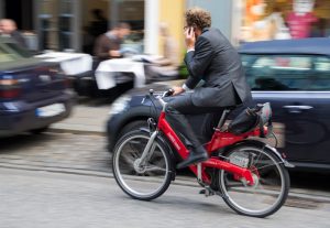 Cyclist wearing business suit riding through traffic while on phone